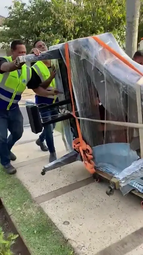 Equipe carregando móvel embalado no jardim de um prédio