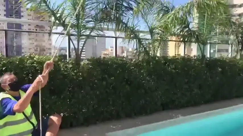 Equipe içando móvel embalado com guincho, ao lado da piscina de um prédio